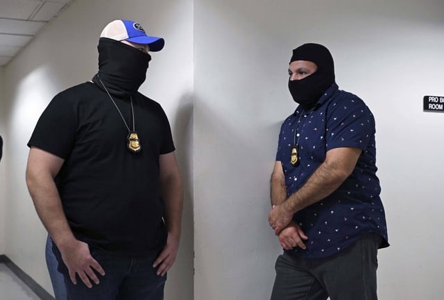 Masked federal agents wait inn the hallways outside the Immigration Courtrooms at Federal Plaza in Lower Manhattan, New York City on September 18, 2025.