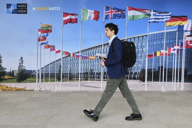A man walks by a mural with flags of NATO member countries at NATO headquarters in Brussels, Tuesday, Sept. 23, 2025. (AP Photo/Virginia Mayo)