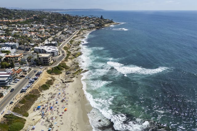 Stock Image: In an aerial photo, people sunbathe on the sand at La Jolla's Windansea Beach during a summer heat wave on September 6, 2025 in San Diego, California.