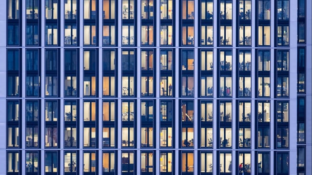 Menschen arbeiten an ihren Schreibtischen in einem Bürohaus.