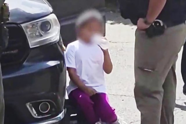 A young girl is surrounded by law enforcement agents outside a house in Leominster, Mass.