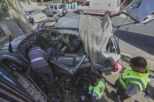 Civil defense workers inspect a damaged car hit Sunday in an Israeli drone strike that killed four members of the same family, in Bint Jbeil town, southern Lebanon, Monday, Sept. 22, 2025. (AP Photo/Mohammed Zaatari)