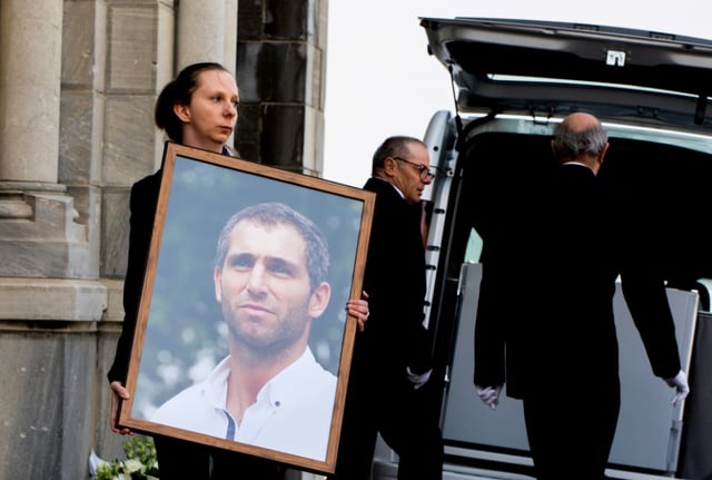 Une femme tient le portrait du joueur de rugby argentin Federico Martin Aramburu lors de ses funérailles le 26 mars 2022 à Biarritz dans le sud-ouest de la France.