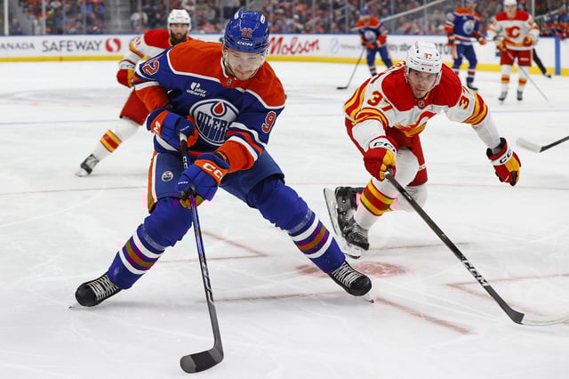 Sep 21, 2025; Edmonton, Alberta, CAN; Edmonton Oilers forward Vasily Podkolzin (92) protects the puck from Calgary Flames defensemen Yan Kuznetsov (37) during the first period at Rogers Place. Mandatory Credit: Perry Nelson-Imagn Images/File photo