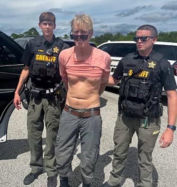Ryan W. Routh, suspected of attempting to assassinate U.S. President Donald Trump at his West Palm Beach golf course, stands handcuffed between two Martin County Sheriff's office deputies after his arrest during a traffic stop near Palm City, Florida, U.S., September 15, 2024. Martin County Sheriff's Office/Handout via REUTERS/File Photo
