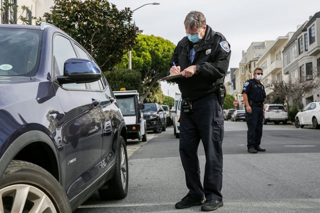 Parking control officer Dan Ryan cites a vehicle for parking illegally in front of a residence in San Francisco in 2022. A new app shows parking tickets being dispensed in the city in real time.