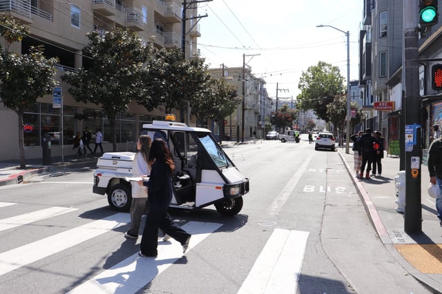 Pedestrians pass by a parking enforcement vehicle on Mission Street. Photo by Marina Newman.