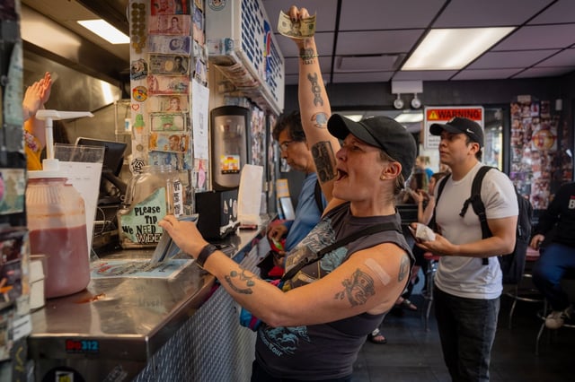 Val Capone tips the staff at The Wieners Circle as the restaurant fulfills its promise to give out free hot dogs on Sept. 23, 2025, after the Bears' Caleb Williams threw four touchdown passes in Sunday's game. (E. Jason Wambsgans/Chicago Tribune)