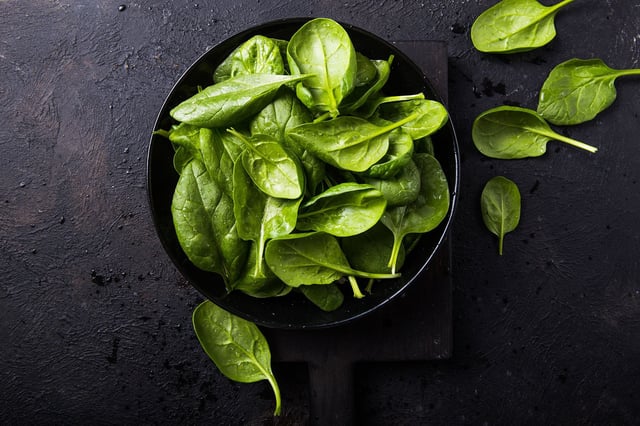 Fresh baby spinach on a plate. Juicy spinach leaves. Diet concept. Vegan food.