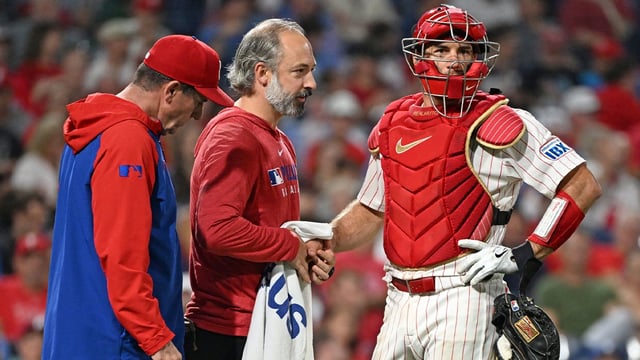 Sep 23, 2025; Philadelphia, Pennsylvania, USA; Philadelphia Phillies trainer Joe Rauch works on the hand of catcher J.T. Realmuto (10) after being injured during the ninth inning against the Miami Marlins at Citizens Bank Park. Mandatory Credit: Eric Hartline-Imagn Images.