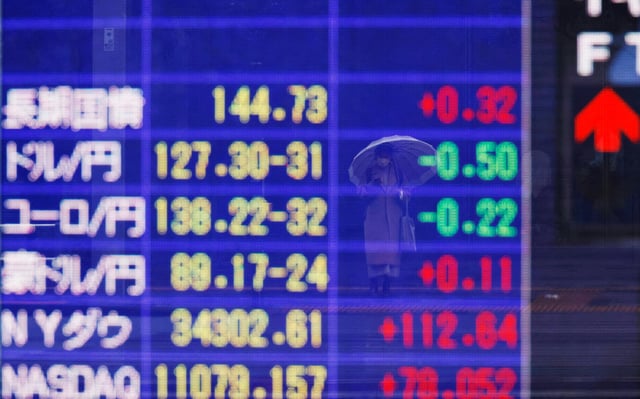 A woman is reflected on an electric board displaying Japan's long-term government bonds level and Japanese Yen rate against U.S. dollar and other currencies outside a brokerage in Tokyo, Japan January 16, 2023. REUTERS/Kim Kyung-Hoon/File Photo