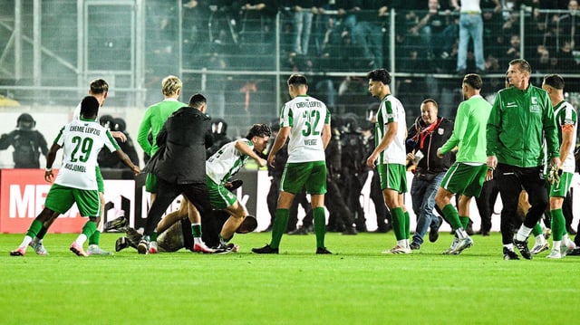 ein Mann liegt am Boden im Stadioninnenraum und Spieler ringsum 