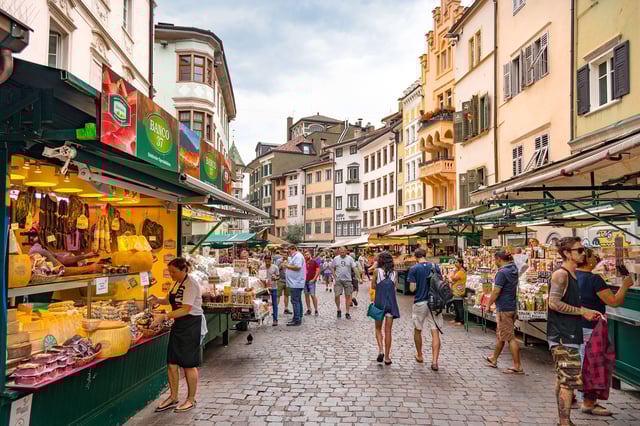 BOLZANO, ITALY - JULY 17, 2018: People shopping at a market on Piazza delle Erbe (Market Square in Italian), in the historic city center of Bolzano - stock photo