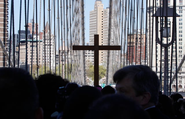 A replica cross rises above the crowd during the "Way of the Cross" procession across the Brooklyn Bridge on Friday, April 6, 2012 in New York.