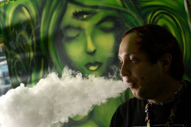 Darren Blake, who works at Myxed Up Creations, uses a vaping product at the store in Denver on Wednesday, Oct. 20, 2021. The Denver City Council is considering a ban on all flavored tobacco products, including vape juice. The proposal is part of a years-long battle from groups fighting teen vaping. The ban would prohibit the sale of flavored vape juice in Denver, along with products that are chewed or smoked. Phil Guerin, owner and founder of Myxed Up Creations, says this ban would destroy his business on East Colfax. He's been in operation for 29 years. Guerin and other vape supporters argue that vaping is safer than cigarettes and they actually help people quit smoking. His Denver store employs 12 people.
