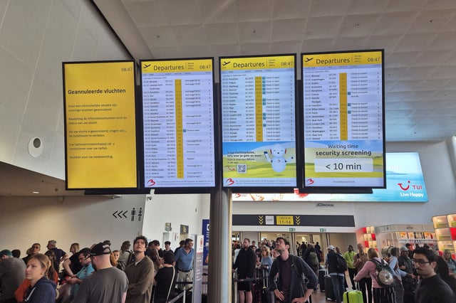 This photograph shows passengers waiting next to a flight information board of the Brussels Airport in Brussels on September 20, 2025, after the airport's system was hit by a "cyberattack" overnight on September 19. (Image: JORIS SMETS/Belga/AFP via Getty Images)