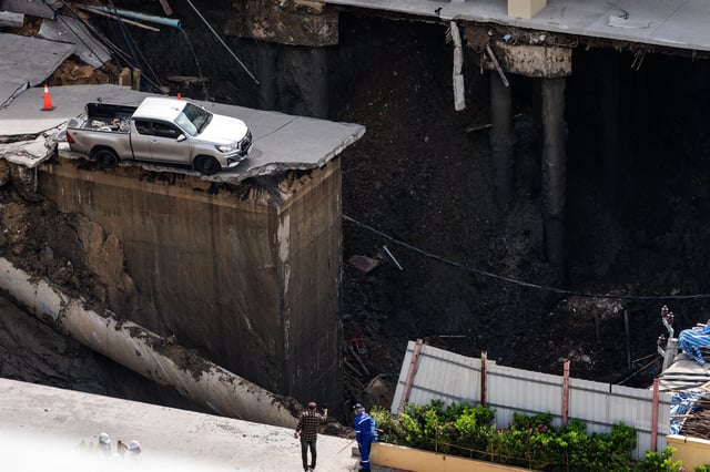 Un hombre toma una fotografía de un agujero en el suelo después del derrumbe de una carretera cerca de un hospital en Bangkok, en Tailandia, el 24 de septiembre de 2025. (Foto de Chanakarn Laosarakham / AFP).
