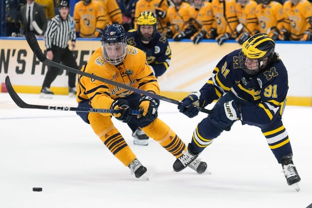 Quinnipiac defenseman Charles-Alexis Legault (6) strips the puck away from Michigan forward Frank Nazar III (91) during the first period of an NCAA semifinal game in the Frozen Four college hockey tournament Thursday, April 6, 2023, in Tampa, Fla. (AP Photo/Chris O'Meara)