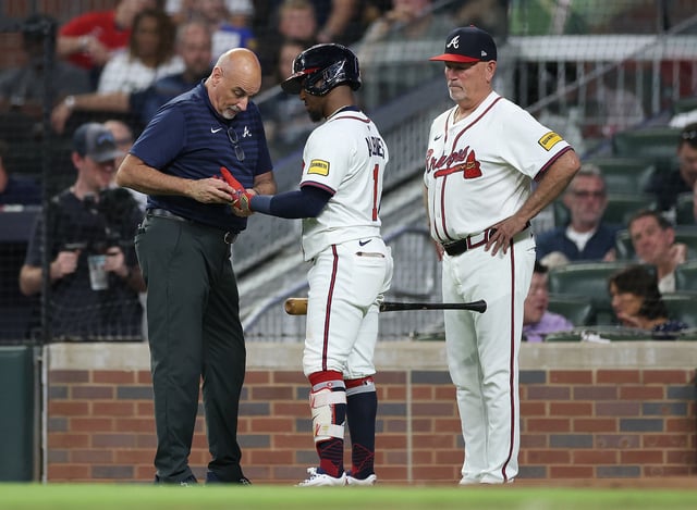 ATLANTA, GEORGIA - SEPTEMBER 22:  Manager Brian Snitker #43 of the Atlanta Braves looks on as head trainer George Poulis​​ checks out the hand of Ozzie Albies #1 during the third inning against the Washington Nationals at Truist Park on September 22, 2025 in Atlanta, Georgia.  Albies left the game after the injury. 
 (Photo by Kevin C. Cox/Getty Images)
