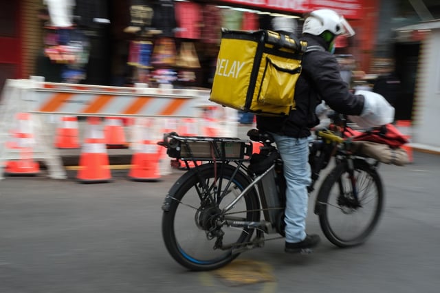 A delivery person rides an electric bicycle through the streets of Manhattan on November 15, 2022 in New York City. (Photo by Spencer Platt/Getty Images)