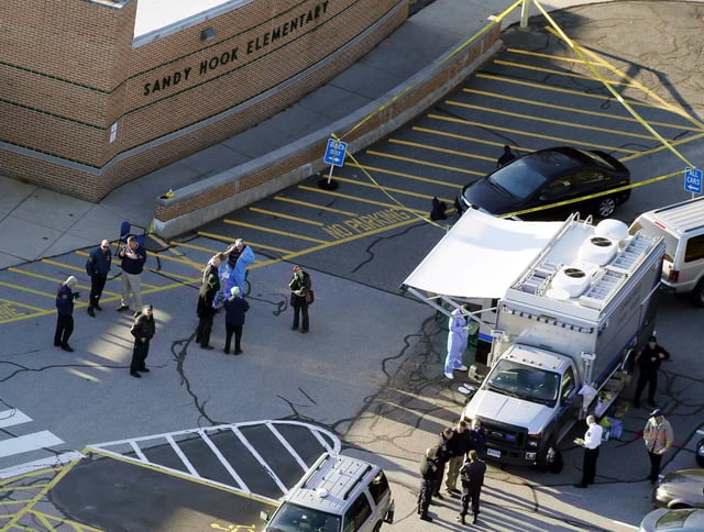 In this Dec. 14, 2012, file photo, officials stand outside of Sandy Hook Elementary School after a shooting in Newtown, Connecticut.