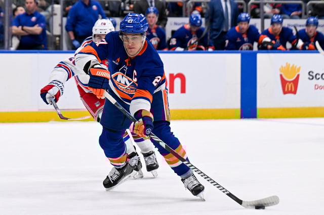 Apr 10, 2025; Elmont, New York, USA;  New York Islanders left wing Anders Lee (27) passes the puck against the New York Rangers during the second period at UBS Arena. Mandatory Credit: Dennis Schneidler-Imagn Images/File Photo