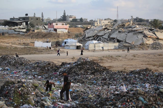 People sift through the rubbish near tents and makeshift shelters at the Bureij camp for Palestinian refugees in the Gaza Strip on September 21, 2025.