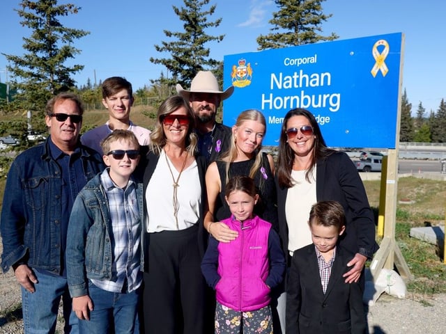  Family of Corporal Nathan Hornburg near a bridge honouring his memory and service.