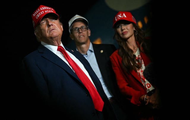 US Secretary of Homeland Security Kristi Noem (R) watches US President Donald Trump talk to journalists as they arrive at Joint Base Andrews, Maryland early on July 4, 2025. Trump returns from Iowa where he spoke at the Salute to America Celebration at the Iowa State Fairgrounds in Des Moines. (Photo by ANDREW CABALLERO-REYNOLDS / AFP) (Photo by ANDREW CABALLERO-REYNOLDS/AFP via Getty Images)