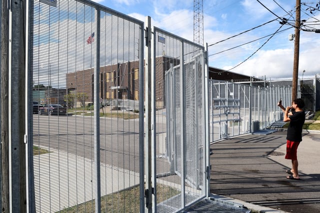 A man records the scene with his cellphone through fencing outside the Immigration and Customs Enforcement facility in Broadview, Sept. 24, 2025.  (Antonio Perez/Chicago Tribune)