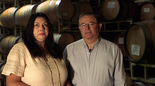 Carlos and Linda Chavez stand in front of barrels bearing the name Chavez Family Cellars in Healdsburg.