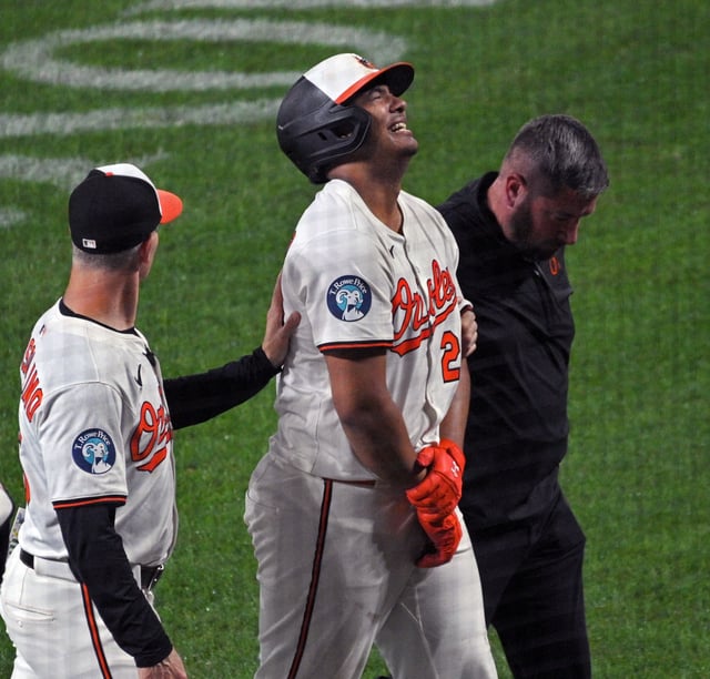 Orioles’ Samuel Basallo, center, grimaces in pain as he walks to the dugout with trainer and interim manager Tony Mandolin, left, after Basallo was hit by a pitch in the ninth inning at Oriole Park at Camden Yards. (Kenneth K. Lam/staff)