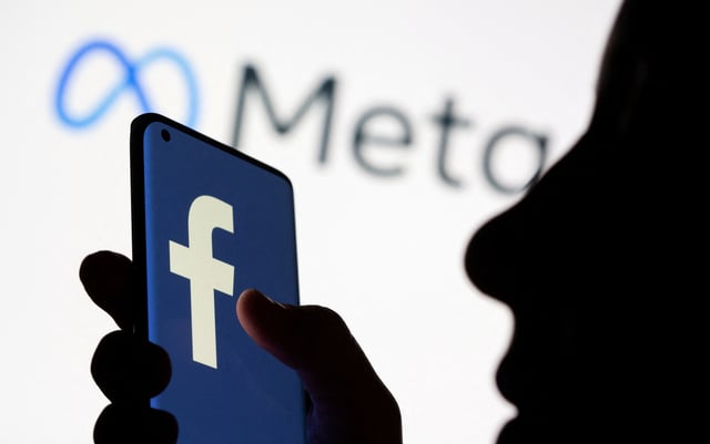 Woman holds smartphone with Facebook logo in front of a displayed logo for Meta in this illustration picture taken October 28, 2021. REUTERS/Dado Ruvic/Illustration/File Photo