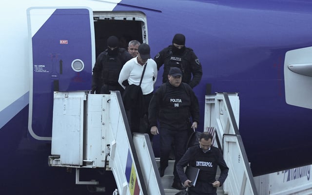 Vladimir Plahotniuc, a Moldovan former lawmaker and business magnate detained on a warrant linked to a fraud case and extradited from Greece, disembarks from a plane together with law enforcement officers upon his arrival, as seen through a window at an airport in Chisinau, Moldova, September 25, 2025. REUTERS/Vladislav Culiomza