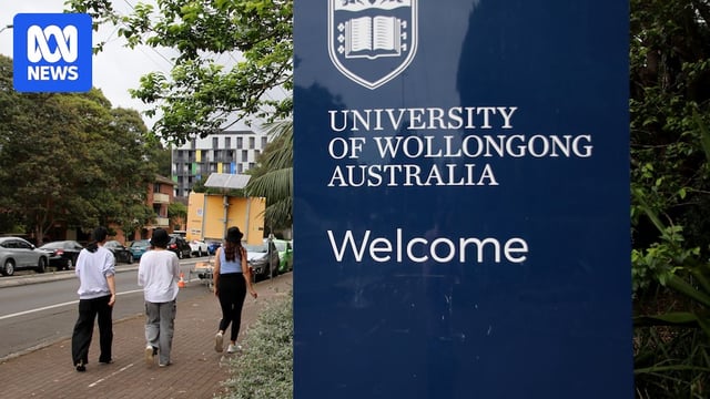 Students walking in carpark, campus sign in foreground