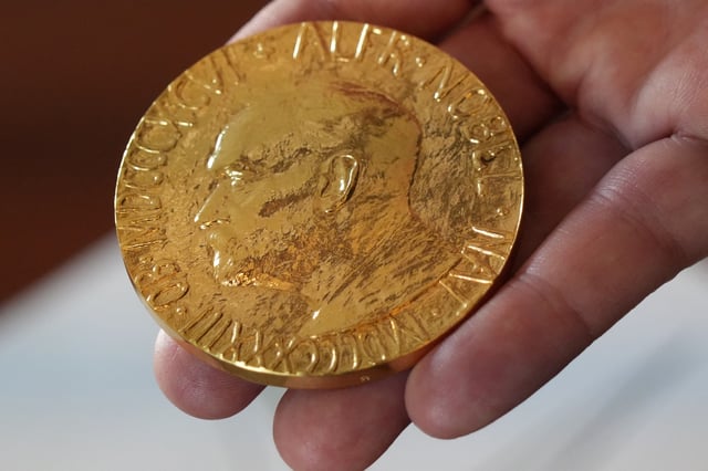 An employee of the Norwegian Nobel Institute holds a replica of a Nobel Peace Medal in the Institute in Oslo, Norway, September 9, 2025. REUTERS/Tom Little