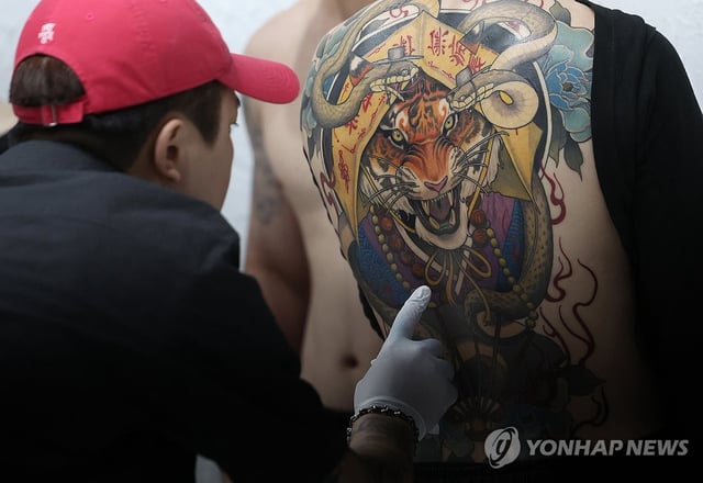 A jury member examines a tattoo on a participant's body during a tattooing contest at the 2025 Korea Tattoo Festival in Seoul in this Aug. 31, 2025, file photo. (Yonhap)