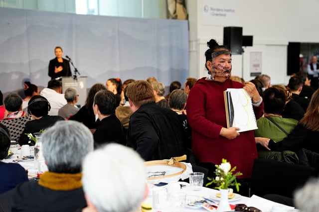 An Inuit woman stands with her back towards Denmark's Prime Minister, Mette Frederiksen, left, as she talks during a meeting in a cultural center in Nuuk, Greenland, on Sept. 24, 2025.