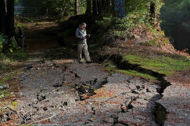 California Geological Survey senior engineering geologist John Oswald, right, assesses damage to a road  Friday, Dec. 6, 2024, in Humboldt County, Calif., following a 7.0 earthquake the day before.