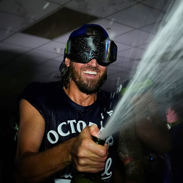 Toronto Blue Jays' Kevin Gausman celebrates with teammates in the clubhouse after their baseball game against the Kansas City Royals, Sunday, Sept. 21, 2025, in Kansas City, Mo. (AP Photo/Charlie Riedel)