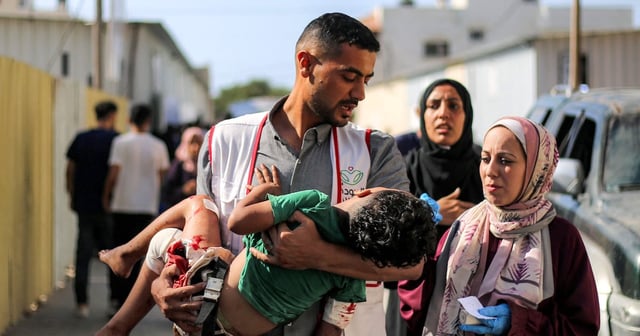 An injured child is carried to Al Awda Hospital in Nuseirat, central Gaza. AFP