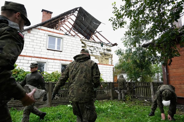 Territorial defense officers pick up debris from the destroyed roof of a house, after Russian drones violated Polish airspace during an attack on Ukraine, in Wyryki near Lublin, Poland, Thursday, Sept. 11, 2025. (AP Photo/Czarek Sokolowski)