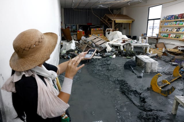 A bookstore staff points at the damage inside her shop in the aftermath of flooding brought by Super Typhoon Ragasa in Hualien, Taiwan, September 26, 2025. REUTERS/Ann Wang