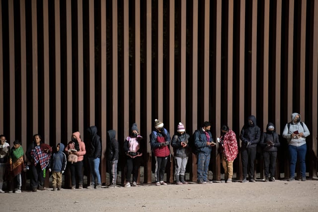 Asylum-seekers line up to be processed by US Customs and Border Patrol agents at a gap in the US-Mexico border fence near Somerton, Arizona, on December 26, 2022.