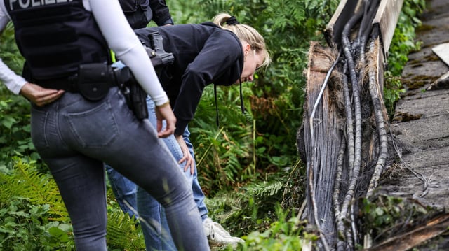 Polizeibeamte an einem ausgebrannten Kabeltunnel neben einem Gleis