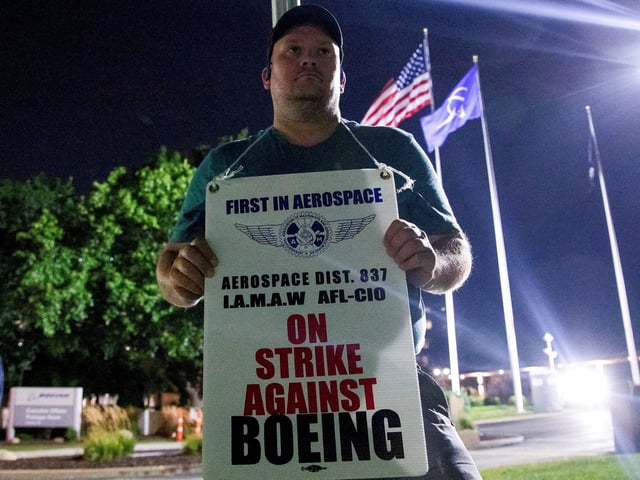 A worker holds a picket sign, as people protest during a walkout by members of the International Association of Machinists and Aerospace Workers (IAM) over contract negotiations, outside Boeing company's facility, in Berkeley, Missouri, U.S., August 4, 2025 REUTERS/Lawrence Bryant/File Photo
