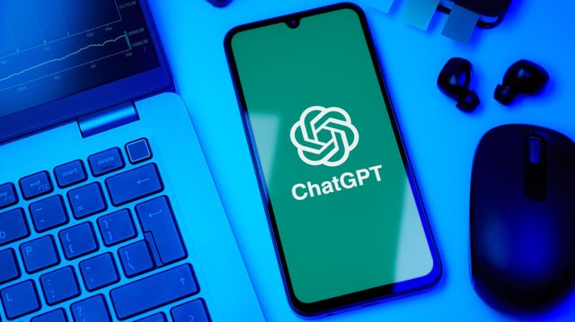 ChatGPT logo on smartphone next to a laptop