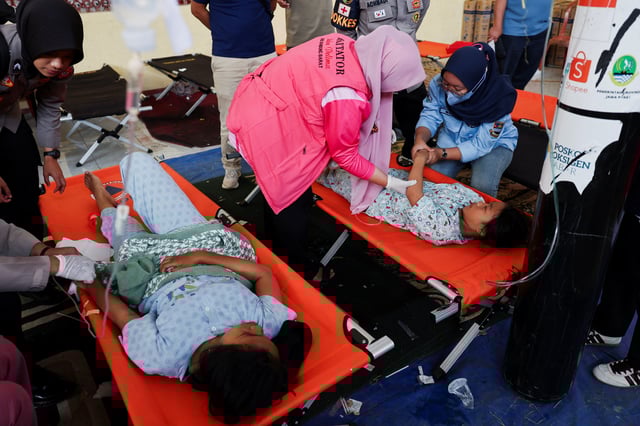 Students receive treatments for food poisoning after eating government-sponsored free school meals, at a makeshift clinic inside a district's hall in Bandung, West Java province, Indonesia, September 25, 2025. REUTERS/Willy Kurniawan