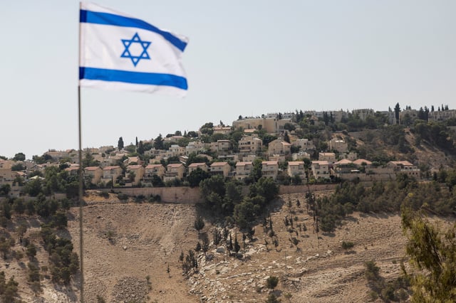 An Israeli flag flutters, as part of the Israeli settlement of Maale Adumim is visible in the background, in the Israeli-occupied West Bank, August 14, 2025. REUTERS/Ronen Zvulun/File Photo