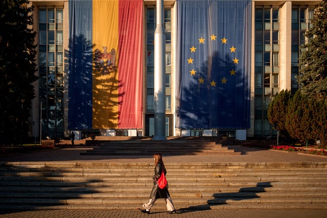 A woman walks in front of the government building, decorated with European Union and Moldovan flags, in Chisinau, Moldova, Friday, Sept. 26, 2025, ahead of parliamentary elections taking place on Sept. 28. (AP Photo/Vadim Ghirda)